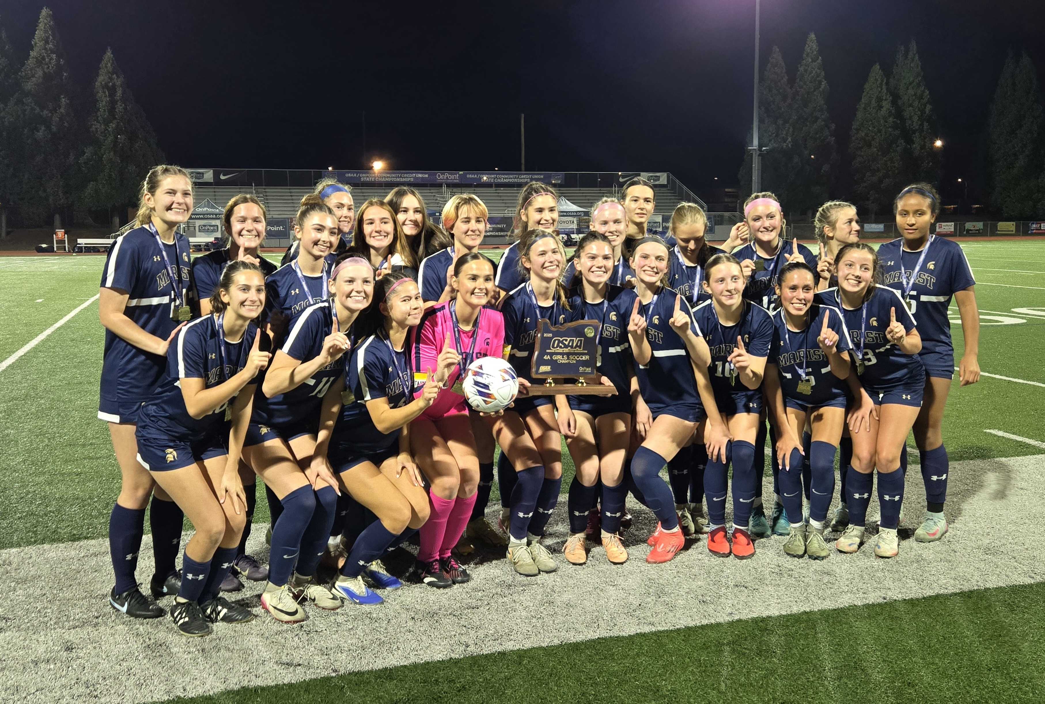 The Marist Catholic girls soccer team celebrates with the trophy after winning the 4A state title. (Photo by Austin White)