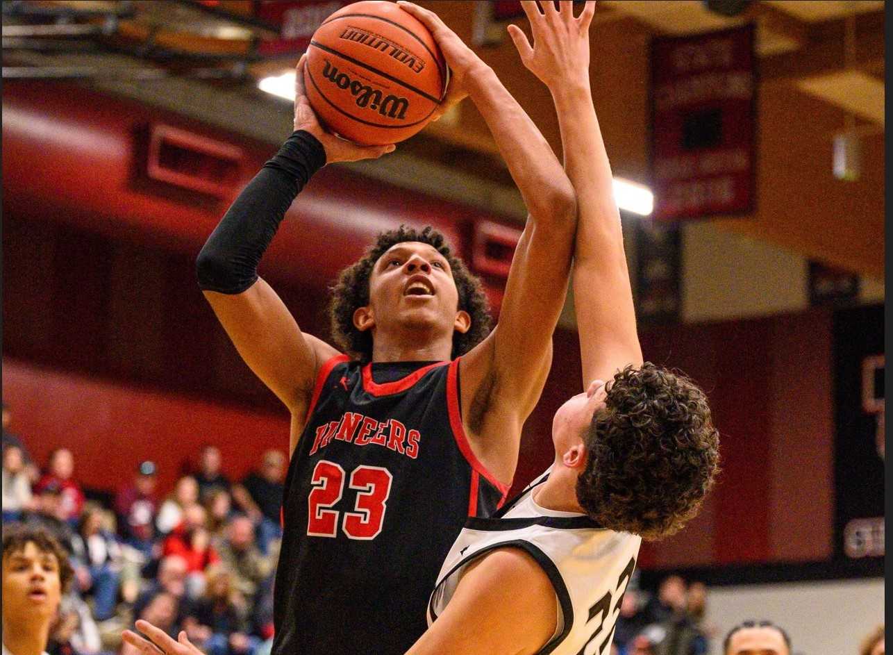 Oregon City junior Alarion Scott turns to shoot over Tualatin sophomore Lincoln Keeney on Tuesday. (Photo by Todd Hiestand)