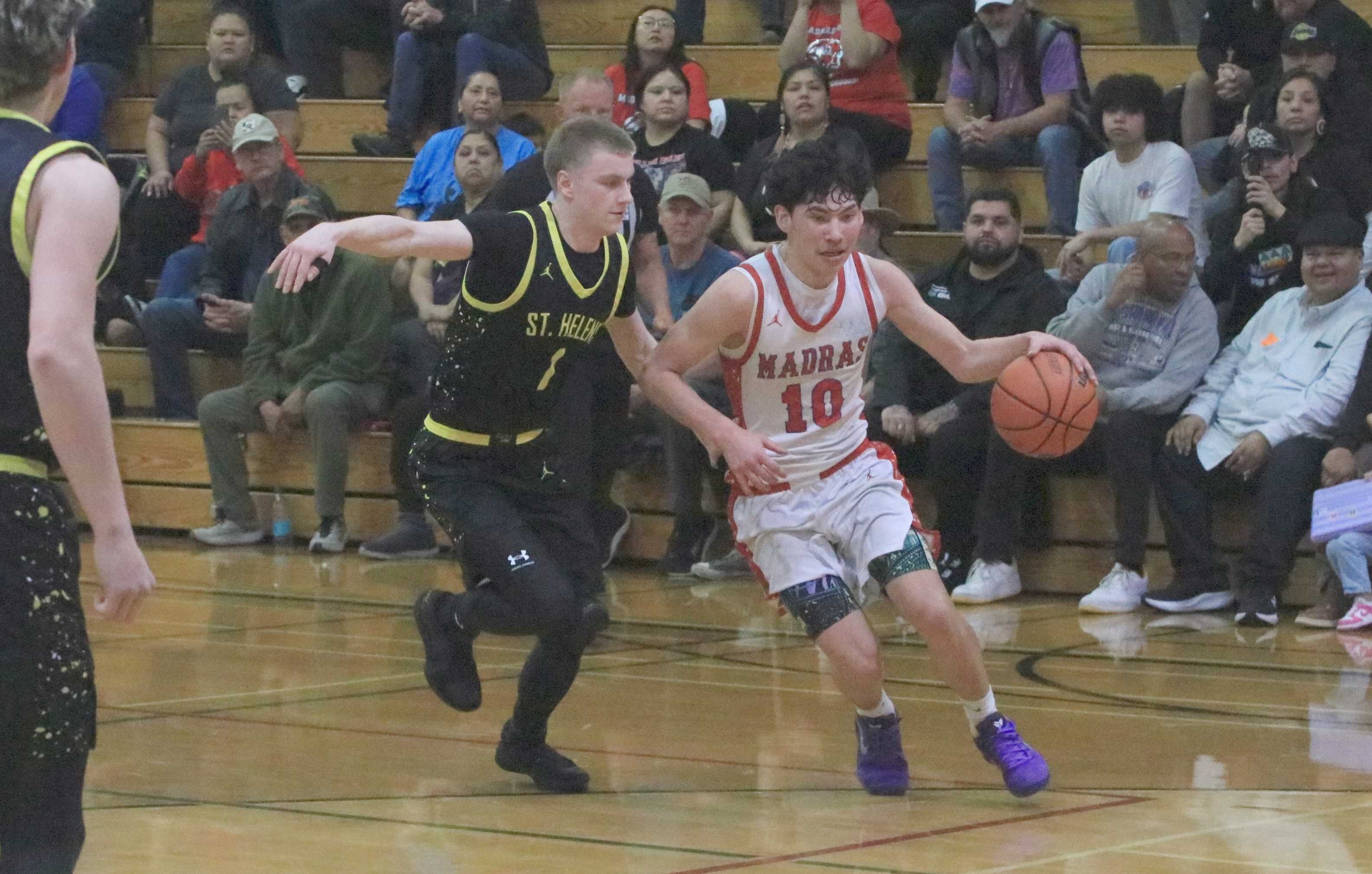 Madras' John Buffalo-Ball (10) drives around St. Helens' Noah Bigham during Thursday's 4A boys basketball quarterfinal.