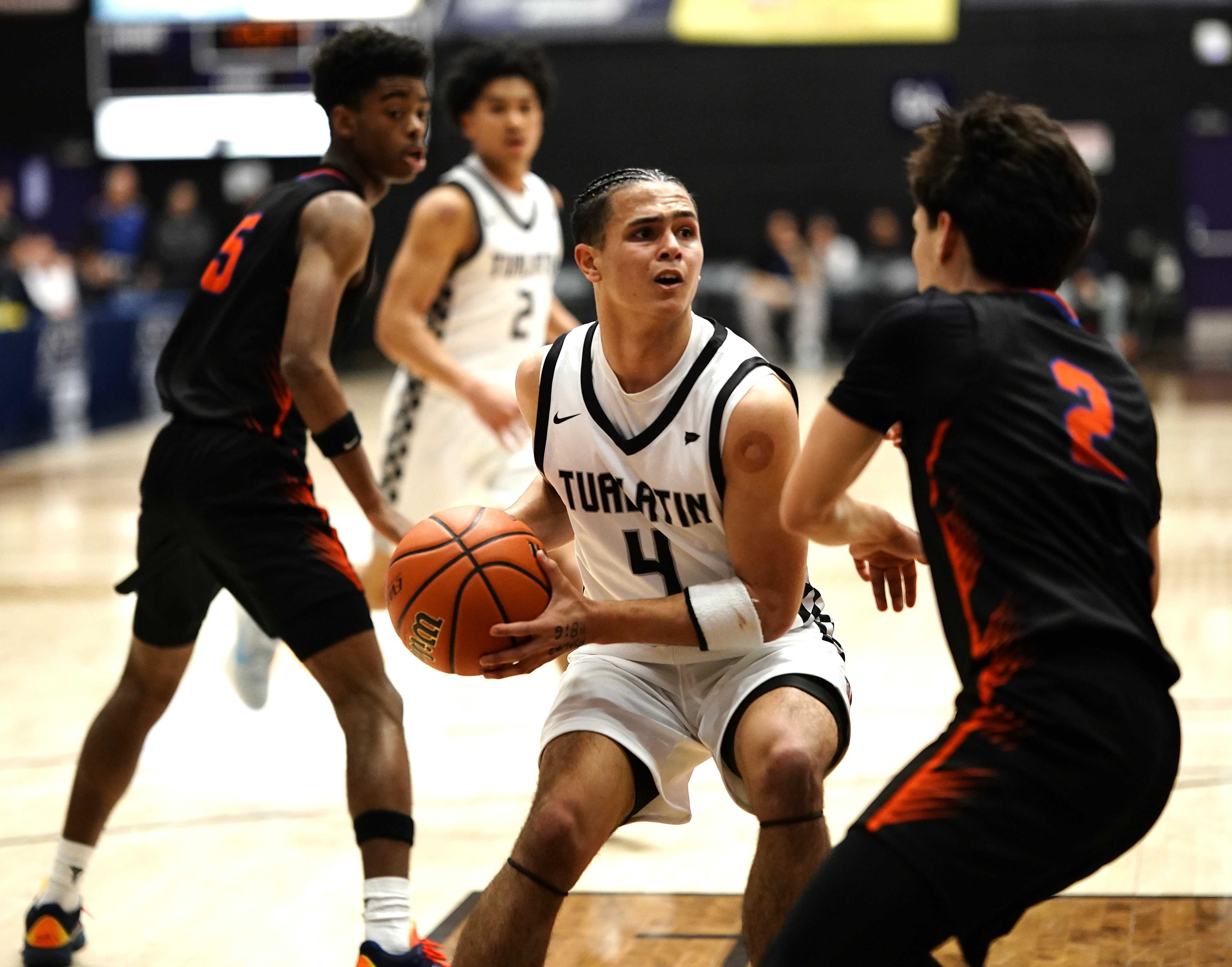 Tualatin guard Carter Lemon (4) drives against Benson's Robert Acelar (2) in Friday's semifinal game. (Photo by J.R. Olson)